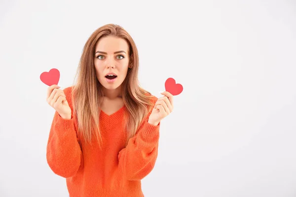 Beautiful surprised young woman with small red hearts on white background — ストック写真