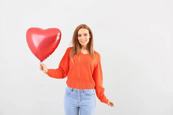 Beautiful young woman with heart-shaped balloon on white background — ストック写真