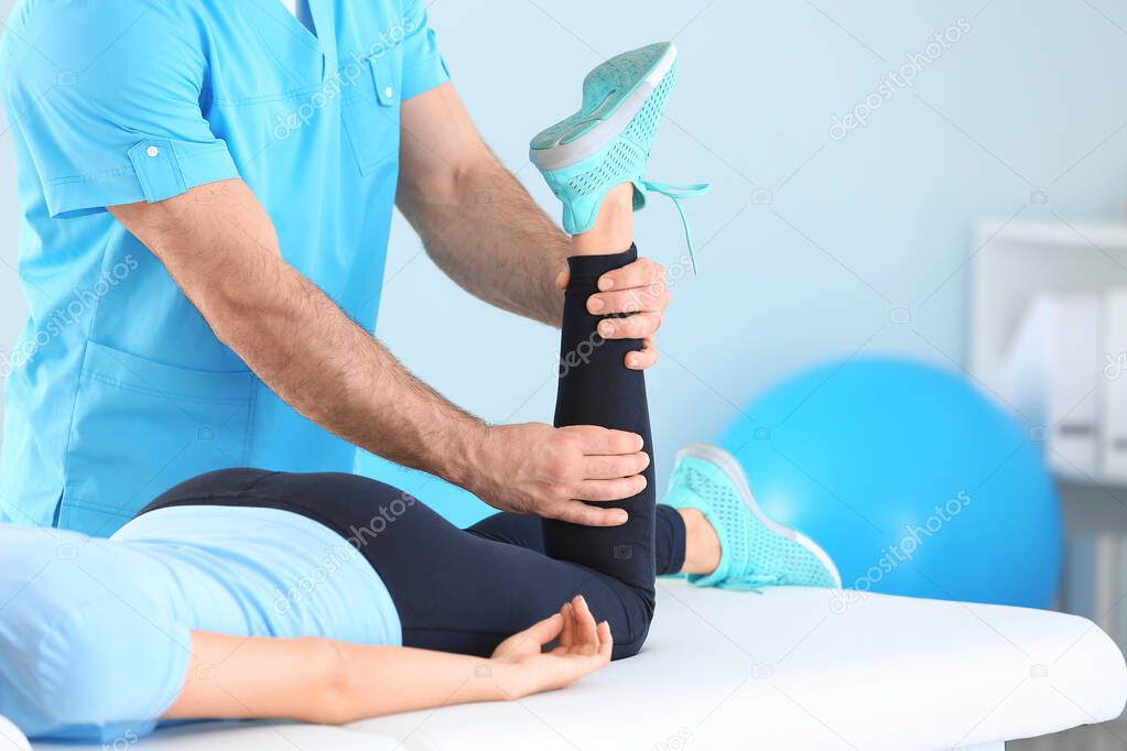 Physiotherapist working with female patient in rehabilitation center