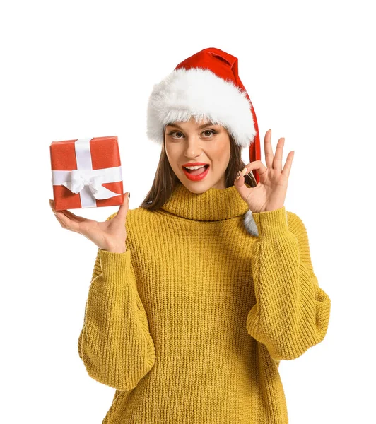 Mulher bonita em chapéu de Santa e com presente de Natal mostrando OK no fundo branco — Fotografia de Stock