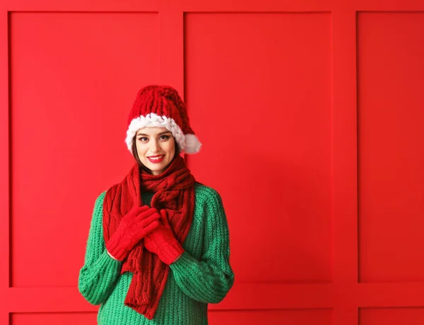 Beautiful young woman in Santa hat and warm clothes on color background — Stock Photo, Image