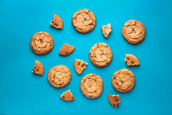 Gustosi biscotti con gocce di cioccolato su sfondo di colore — Foto Stock