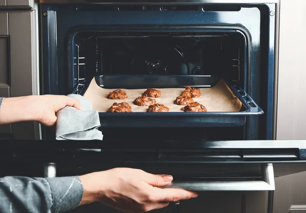 Mujer poniendo bandeja para hornear con galletas crudas en el horno — Foto de Stock