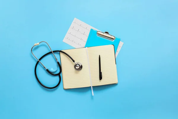 Stetoscopio, notebook e cardiogramma su sfondo a colori. Concetto di cardiologia — Foto Stock