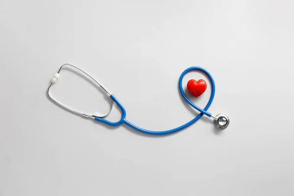 Stethoskop und rotes Herz auf hellem Hintergrund. Kardiologie-Konzept — Stockfoto