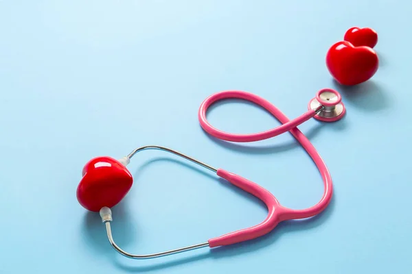 Stethoscope and red hearts on color background. Cardiology concept — Stock Photo, Image