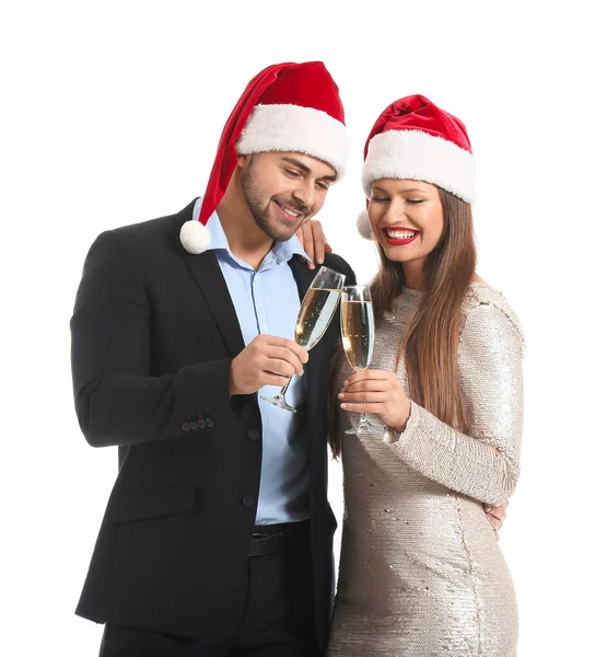 Pareja feliz en sombreros de Santa Claus y con copas de champán sobre fondo blanco — Foto de Stock