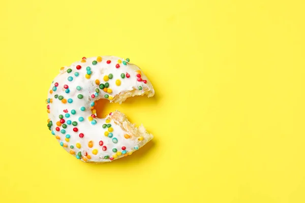 Sweet bitten donut on color background