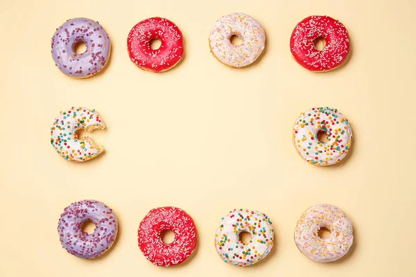 Quadro feito de doces donuts saborosos no fundo de cor — Fotografia de Stock