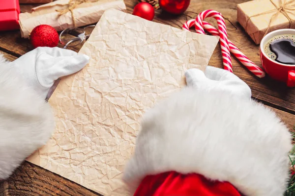 Santa Claus with empty paper sheet on wooden table — Stock Photo, Image