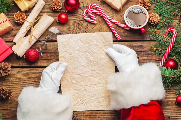 Санта Клаус з порожнім аркушем паперу на дерев "яному столі. — стокове фото
