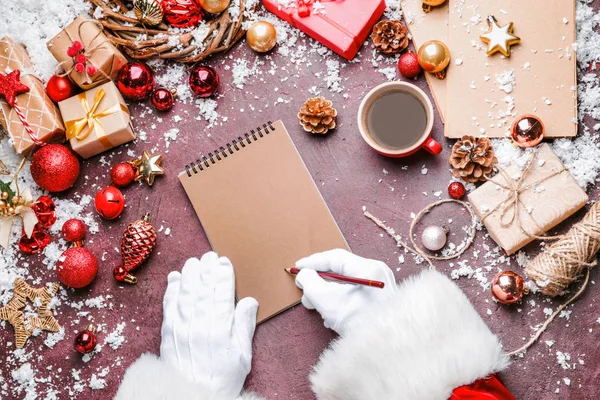 Άγιος Βασίλης γράφει κάτι στο σημειωματάριο στο τραπέζι — Φωτογραφία Αρχείου