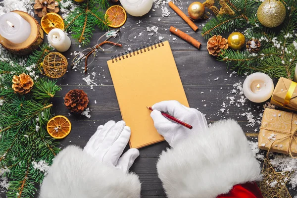 Papá Noel escribiendo algo en el cuaderno en la mesa — Foto de Stock