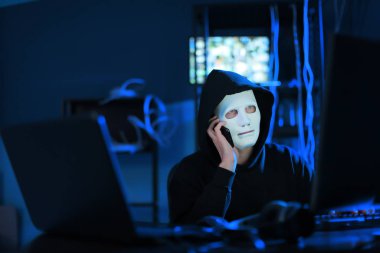 Profesyonel bilgisayar korsanı karanlık odada telefonla konuşuyor.