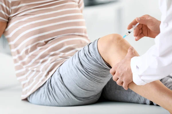 Doctor giving mature woman with joint pain injection in clinic, closeup — Stockfoto