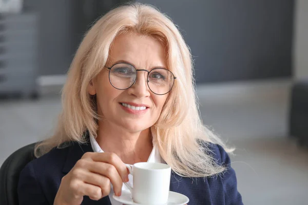 Mature businesswoman drinking coffee in office — Stock Photo, Image