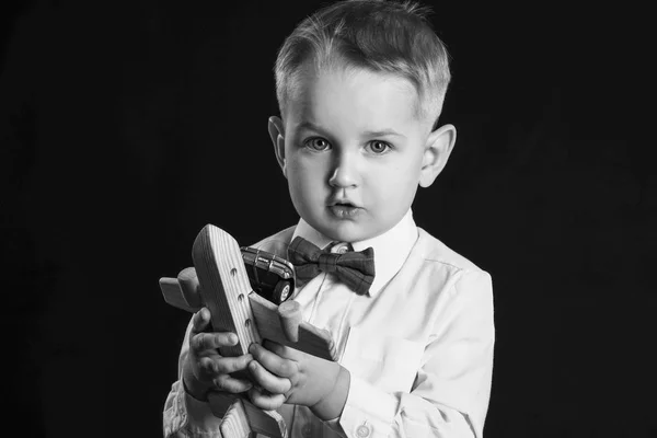 Preto e branco retrato de bonito menino com brinquedo avião no escuro fundo — Fotografia de Stock