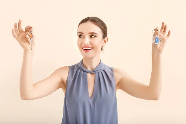 Female real estate agent with keys on light background — Stock Photo, Image