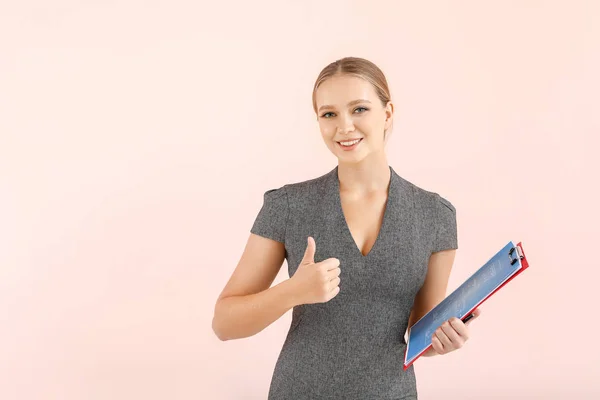 Vrouwelijke makelaar toont duim-up gebaar op kleur achtergrond — Stockfoto