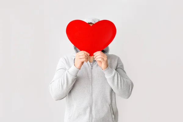 Handsome man with red heart on light background. Valentine's Day celebration — ストック写真