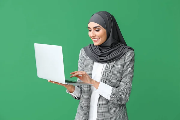 Beautiful Arab woman with laptop on color background