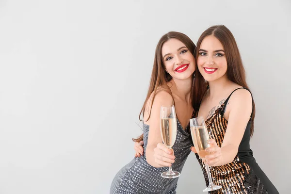 Lindas jovens mulheres com champanhe no fundo claro — Fotografia de Stock