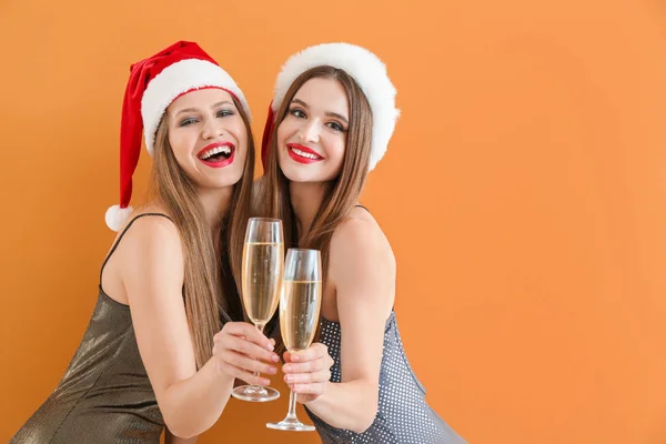 Красиві молоді жінки з шампанським святкують Різдво на кольоровому фоні — стокове фото
