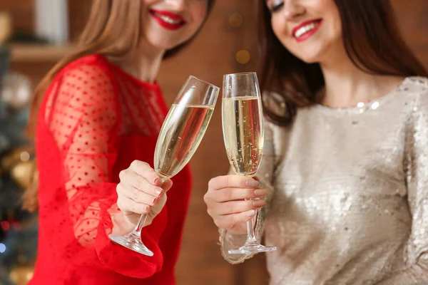 Beautiful young women with champagne celebrating Christmas at home — Stockfoto