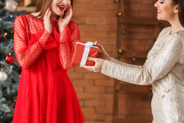 Beautiful young woman greeting her friend on Christmas eve — Stock Photo, Image