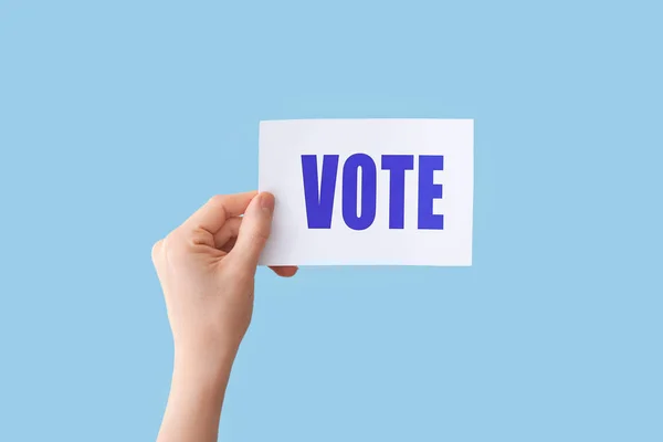 Papel de mão com texto VOTE sobre fundo de cor — Fotografia de Stock