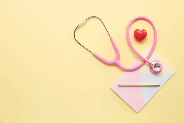 Stethoskop, Herz und Notizbuch auf farbigem Hintergrund. Kardiologie-Konzept — Stockfoto