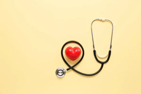 Stethoscope and red heart on color background. Cardiology concept — Stock Photo, Image