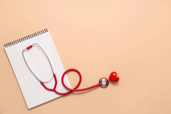 Stethoscope, notebook and red heart on color background. Cardiology concept — Stock Photo, Image
