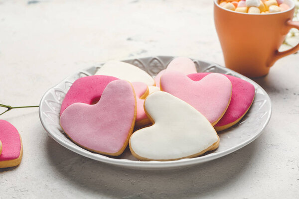 Plate with tasty heart-shaped cookies and cup of cacao on white background. Valentines Day celebration
