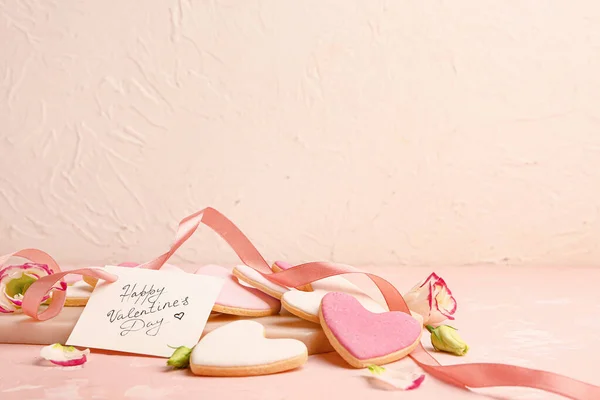 Deska ze smacznymi ciasteczkami w kształcie serca i kartką okolicznościową na stole. Święto Walentynek — Zdjęcie stockowe