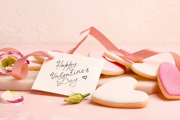 Placa com saborosos biscoitos em forma de coração e cartão de saudação na mesa. Dia dos Namorados celebração — Fotografia de Stock