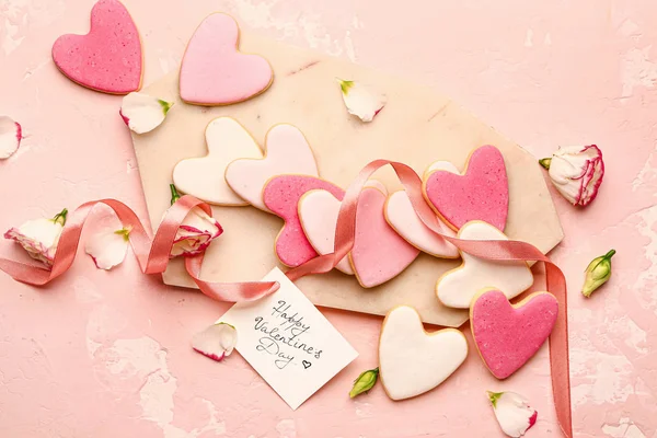 Tablero con sabrosas galletas en forma de corazón y tarjeta de felicitación en el fondo de color. Celebración de San Valentín — Foto de Stock