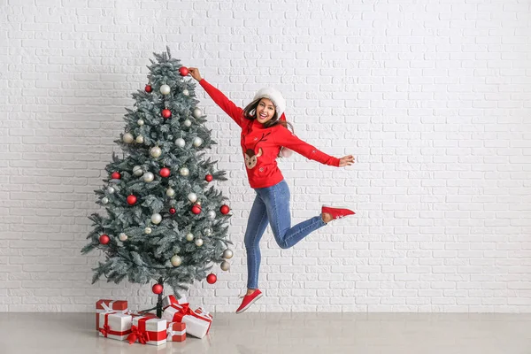 Saut femme décoration arbre de Noël près de mur de briques blanches — Photo