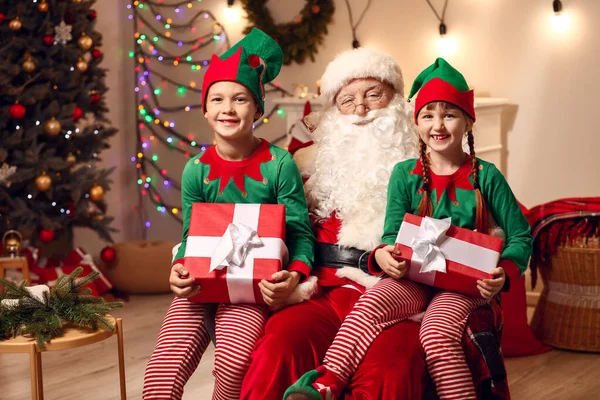 Weihnachtsmann und kleine Wichtelkinder mit Geschenken im weihnachtlich dekorierten Raum — Stockfoto