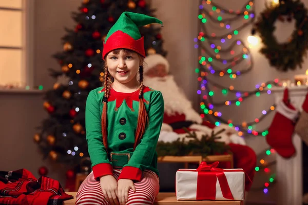 Menina em traje de duende e com presente no quarto decorado para o Natal — Fotografia de Stock