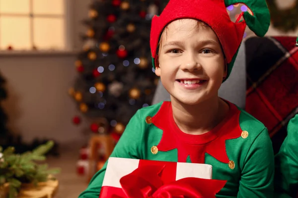 Little boy in costume of elf and with gift in room decorated for Christmas — Stock Photo, Image