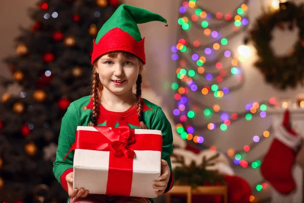 Bambina in costume da elfo e con regalo in camera decorata per Natale — Foto Stock