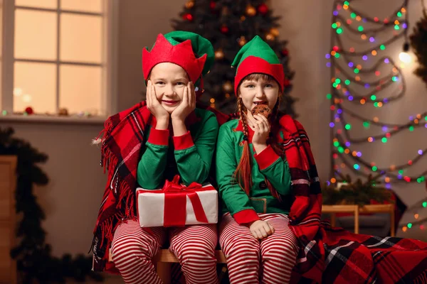 Små barn i alvdräkt, med gåva och kakor på rummet dekorerade till jul — Stockfoto