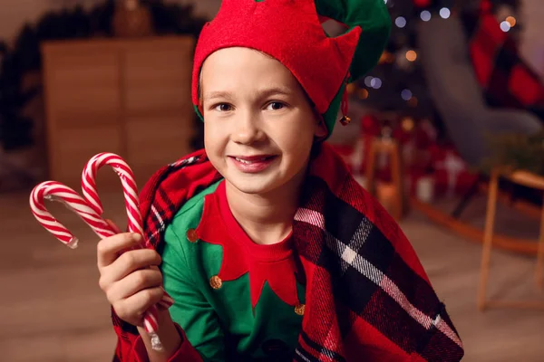 Little boy in costume of elf and with candy canes in room decorated for Christmas — Stock Photo, Image