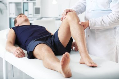 Doctor examining sportsman with joint pain in clinic