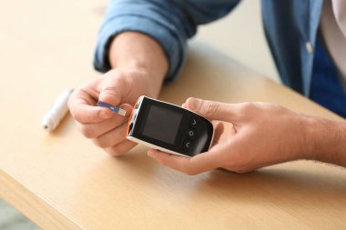 Şeker hastası masadaki kan şekerini ölçüyor.