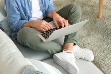 yakışıklı adam evde kanepenin üstünde laptop