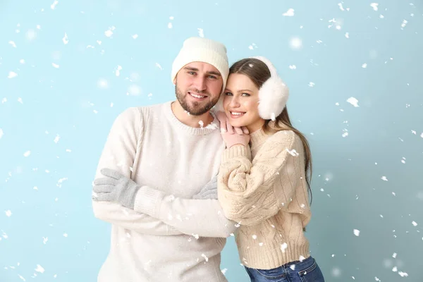 Πορτρέτο του ευτυχισμένου ζευγαριού σε χειμωνιάτικα ρούχα και ιπτάμενο χιόνι στο φόντο χρώμα — Φωτογραφία Αρχείου