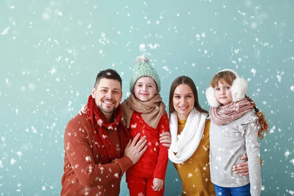 Lycklig familj i vinter kläder och fallande snö på färg bakgrund — Stockfoto