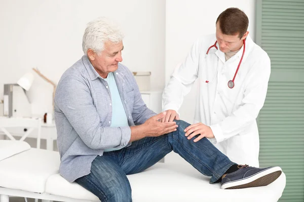 Доктор вивчає зрілого чоловіка з болем в клініці — стокове фото